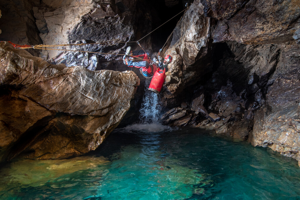 Caver traversing a watery section of a cave